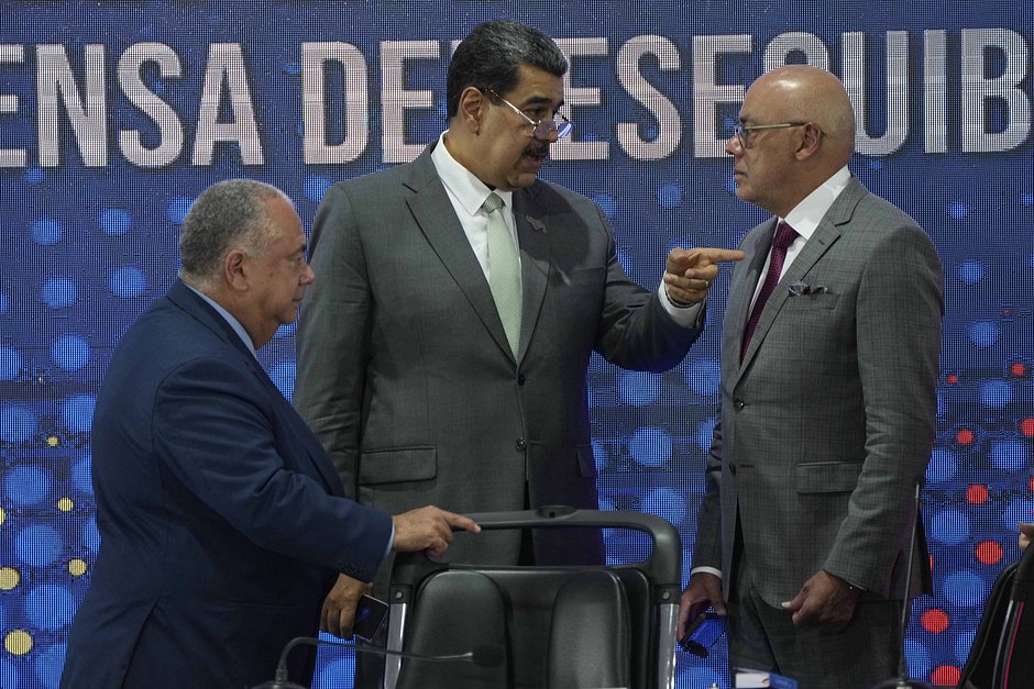 Президент Национального избирательного совета Элвис Хидробо Аморосо (слева) наблюдает, как президент Венесуэлы Николас Мадуро (в центре) разговаривает с председателем Национальной ассамблеи Хорхе Родригесом в Каракасе, Венесуэла, 4 декабря 2023 года