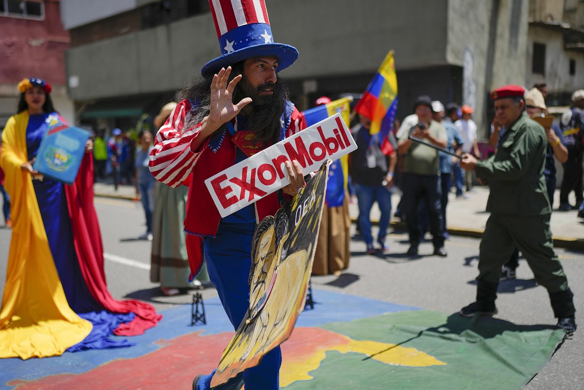 Мужчина в костюме американского персонажа дяди Сэма держит табличку нефтяной компании Exxon во время проправительственного марша под лозунгом «Верните Эссекибо» в Каракасе, Венесуэла, 9 сентября 2023 года