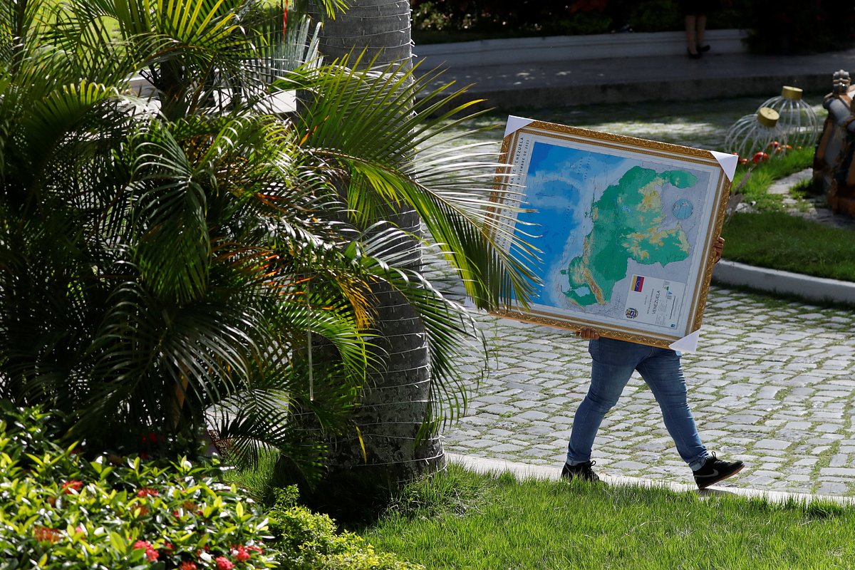 Мужчина несет обновленную карту Венесуэлы в раме, на которой спорный регион Эссекибо изображен как часть Венесуэлы, Каракас, 6 декабря 2023 года