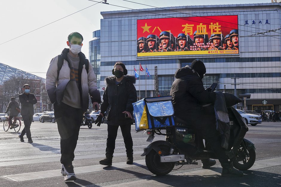 Местные жители проходят мимо большого экрана с рекламой Народно-освободительной армии Китая на торговом центре в Пекине, 9 января 2023 года