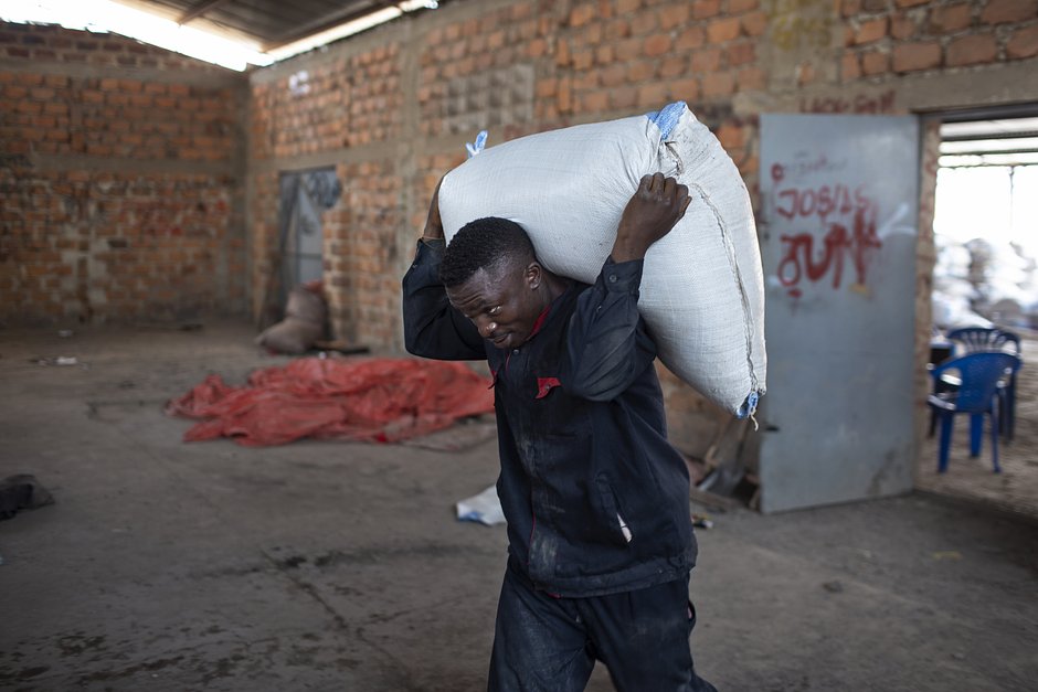 Рабочий несет мешок с кобальтом в складское помещение на рынке Мусомпо на окраине Колвези, ДР Конго, 14 июля 2018 года