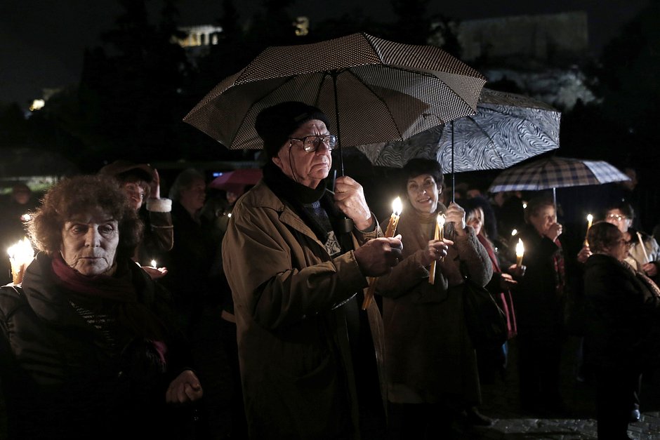 Люди держат свечи во время митинга на фоне Парфенона в Афинах 18 января 2015 года. Около 200 человек собрались перед музеем Акрополя, требуя вернуть на родину достопримечательности Парфенона