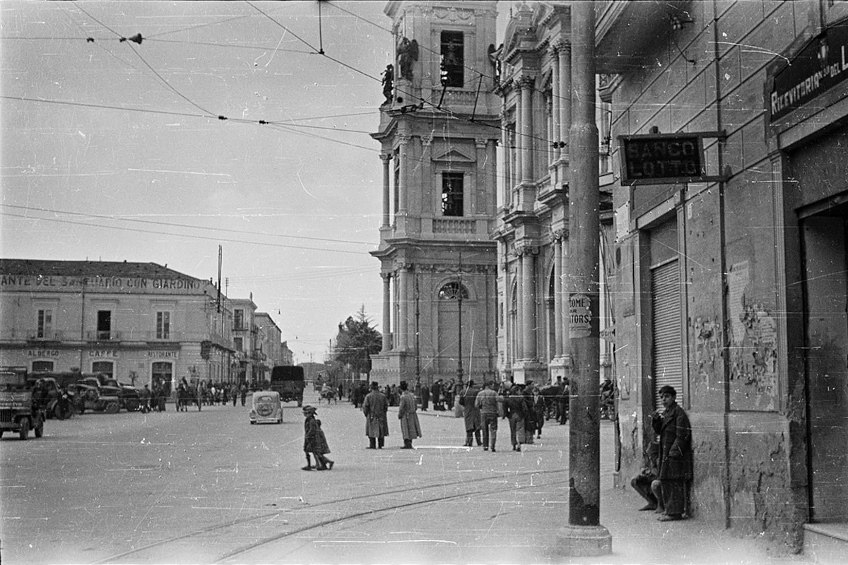 Движение в центре города. Справа видна церковь Девы Марии Розария (итал. Santuario della Beata Vergine del Rosario di Pompei). Слева — американские армейские грузовики и внедорожники. Помпеи, Италия. 1944-45 годы