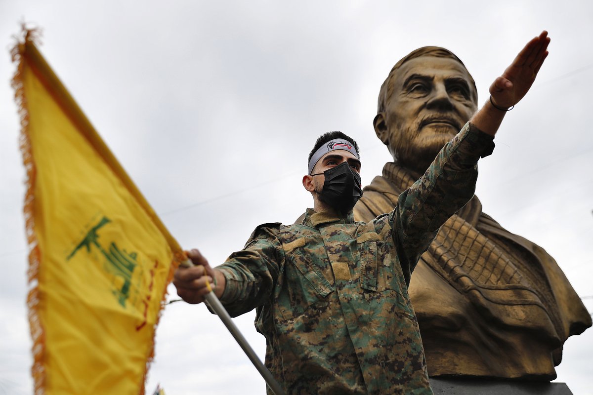 Боец «Хезболлы» держит флаг группировки, стоя перед статуей иранского генерала Касема Сулеймани в южном пригороде Бейрута, Ливан, 4 января 2022 года