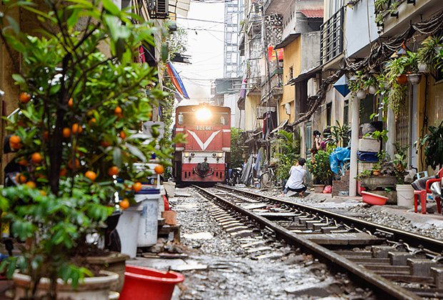 Поезд проходит по узкой улочке между старыми домами в Ханое