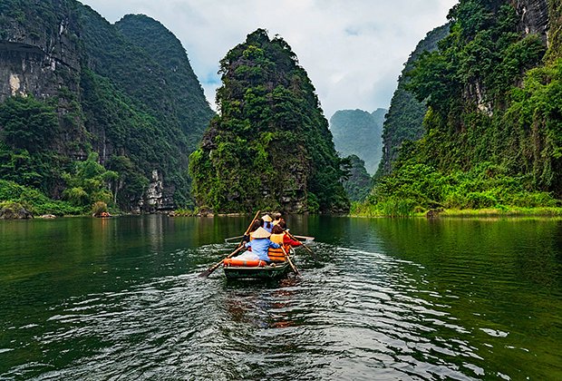 В национальном парке Там Кок туристы гуляют по рисовым полям, окруженным каменными скалами, и совершают мини-круиз по тропикам в бамбуковой лодке