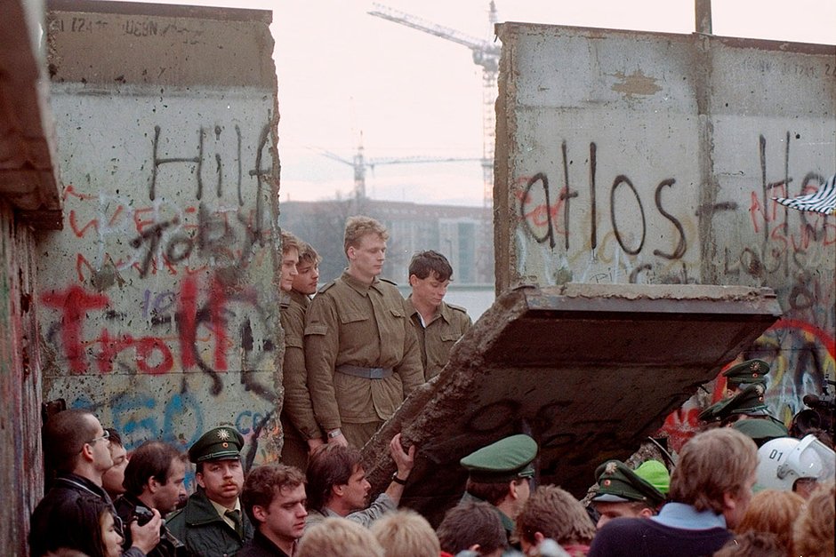 Пограничники ГДР возле бреши в Берлинской стене после того, как демонстранты разрушили ее часть у Бранденбургских ворот, 11 ноября 1989 года