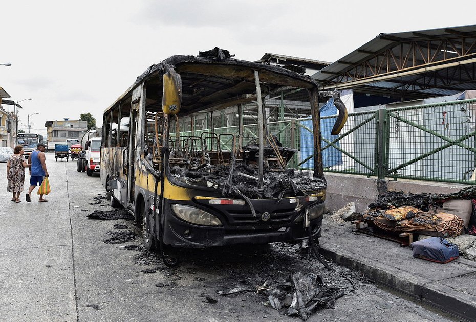 Люди проходят мимо останков сгоревшего автобуса в эквадорском Гуаякиле
