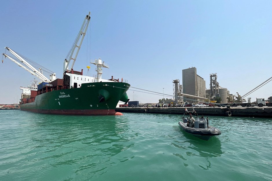 Катер береговой охраны проплывает мимо коммерческого контейнеровоза, пришвартованного в удерживаемом хуситами порту Ходейда на Красном море, Йемен, 25 февраля 2023 года