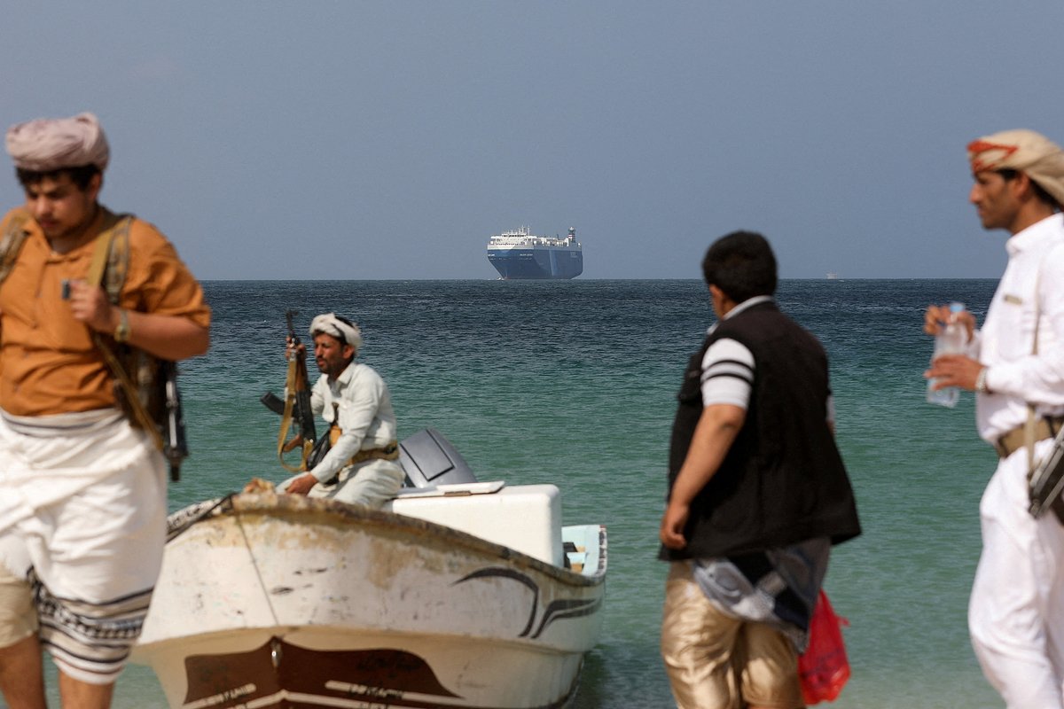 Вооруженные хуситы на пляже. На фоне — захваченное ими торговое судно Galaxy Leader на якоре у побережья Аль-Салифа, Йемен, 5 декабря 2023 года