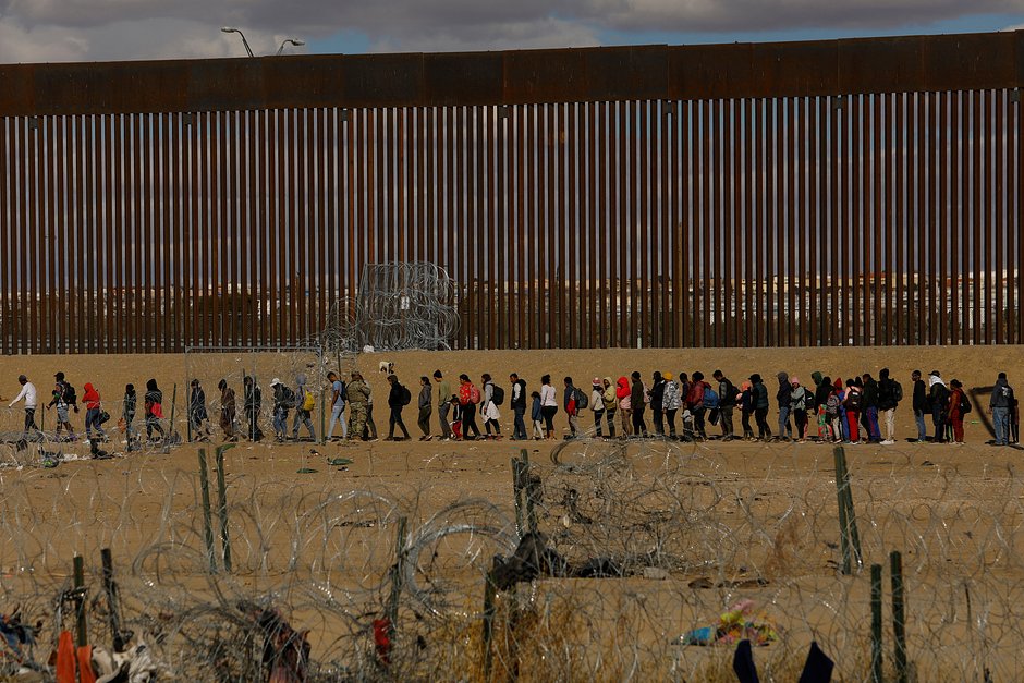 Мигранты возле пограничной стены после пересечения забора из колючей проволоки, установленного для предотвращения их перехода в Соединенные Штаты, вид из Сьюдад-Хуареса, Мексика, 22 января 2024 года