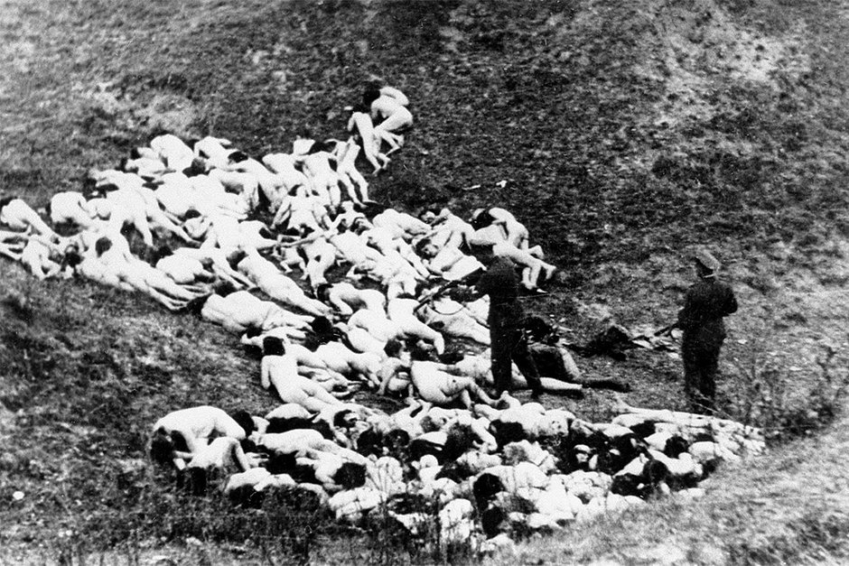 Немецкий полицейский добивает выживших после массовой казни еврейских женщин и детей у села Мизоч Ровенской области, 14 октября 1942 года