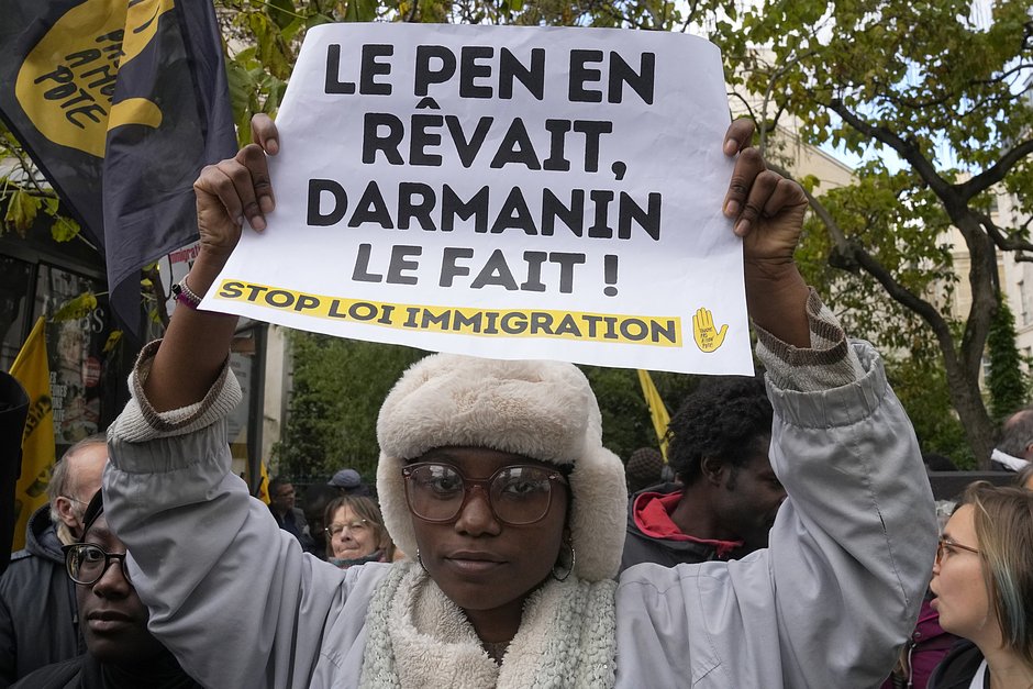 Протестующая держит плакат с надписью «Ле Пен мечтала об этом, Дарманен делает это» во время акции протеста перед зданием Сената в Париже, 6 ноября 2023 года