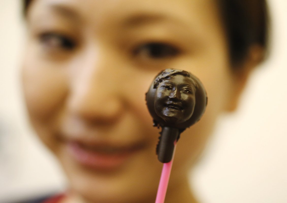 A woman holds a piece of chocolate made in the shape of her face at a workshop ahead of Valentine's Day in Tokyo