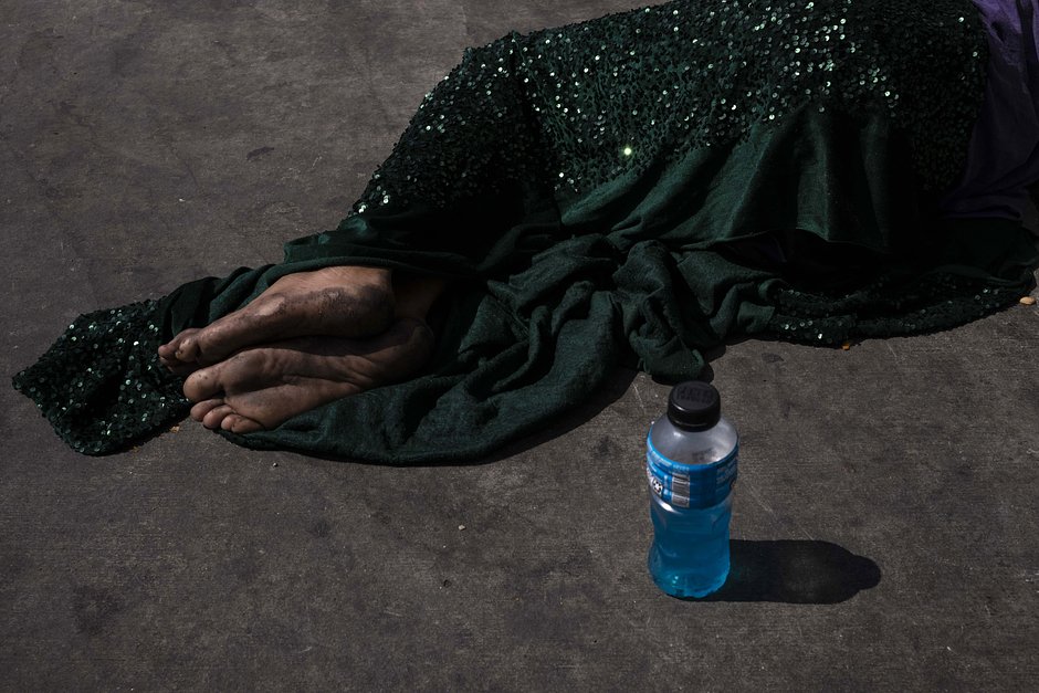 Босоногий бездомный дремлет на тротуаре, укрытый бархатным одеялом, 14 сентября 2023 года
