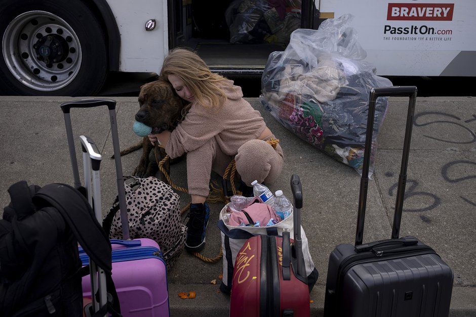 Бездомная Синтия Хьюлетт обнимает свою собаку Макса, ожидая посадки в автобус до ближайшего мотеля после очистки ее палаточного лагеря городскими рабочими в рамках инициативы Inside Safe в Лос-Анджелесе, 24 октября 2023 года