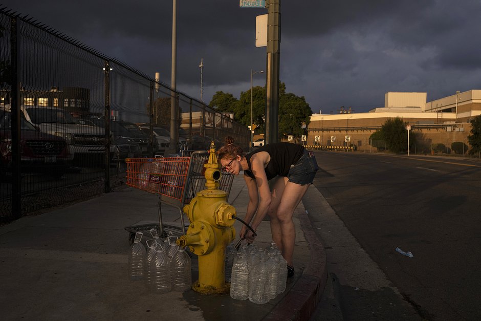 Виктория Филипи, живущая в небольшом кемпинге для бездомных со своими собаками, наполняет бутылки водой из пожарного гидранта в Лос-Анджелесе, 25 октября 2023 года