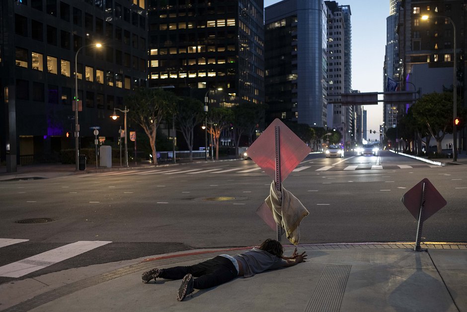 Бездомный кричит и вытягивает руки, лежа на тротуаре в центре Лос-Анджелеса, 13 октября 2023 года