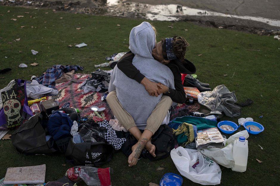 Бездомная пара, которая предпочла не раскрывать свои имена, обнимается среди своих вещей в парке Макартур, Лос-Анджелес, 20 октября 2023 года