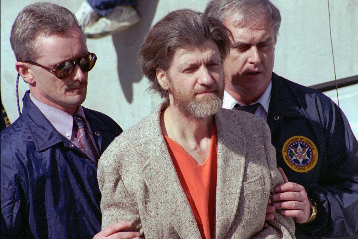 Теодора Качинского окружают федеральные агенты, когда его ведут к машине от здания федерального суда в Хелене, штат Монтана, США, 4 апреля 1996 года