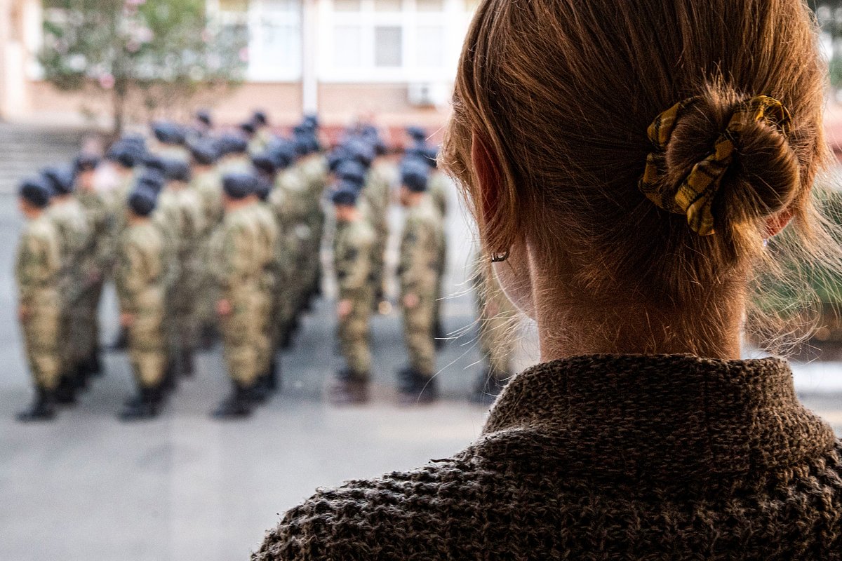 Девушка смотрит на построение призывников перед отправкой на службу в вооруженные силы РФ на территории военного комиссариата в Симферополе