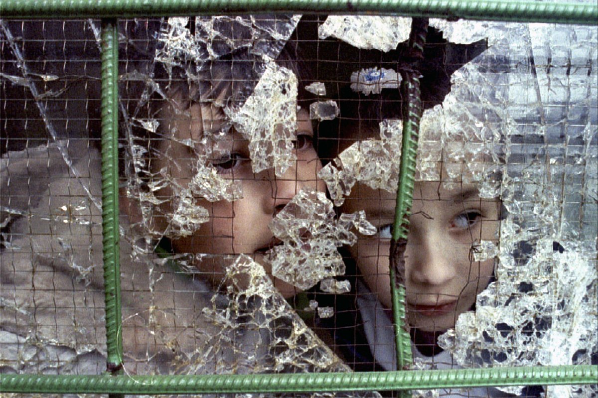 Дети выглядывают из разбитого окна в Сараево, 21 ноября 1992 года