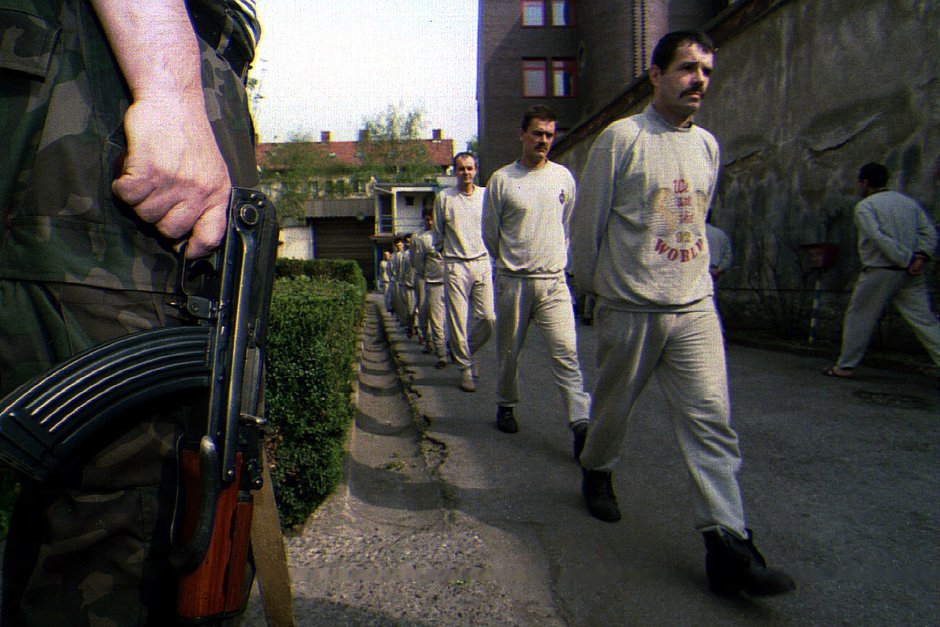 Вооруженный охранник наблюдает за военнопленными боснийскими сербами в тюрьме Тузла, 26 апреля 1993 года