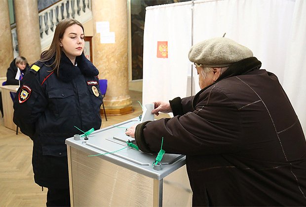 Женщина голосует на выборах президента России на избирательном участке №1022 в здании планетария в Волгограде