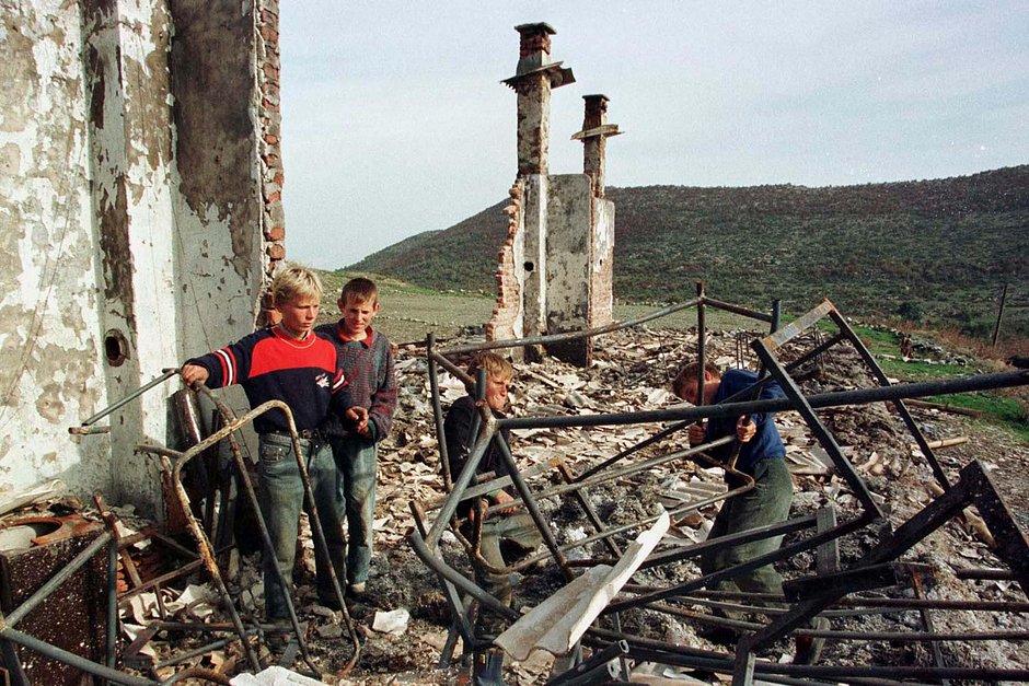 Албанские мальчики разбирают развалины своей сгоревшей школы в деревне Жатрич, примерно в 60 километрах к юго-западу от Приштины, 9 октября 1998 года