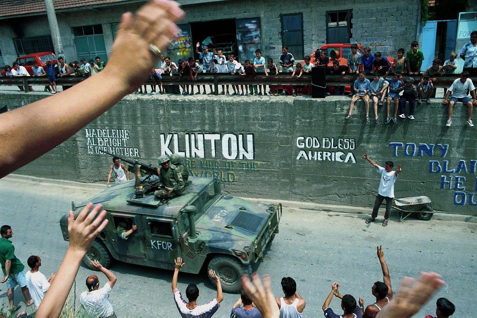 Этнические албанцы приветствуют американские подразделения KFOR, когда они проходят через город Гнилане, Косово, 30 июня 1999 года
