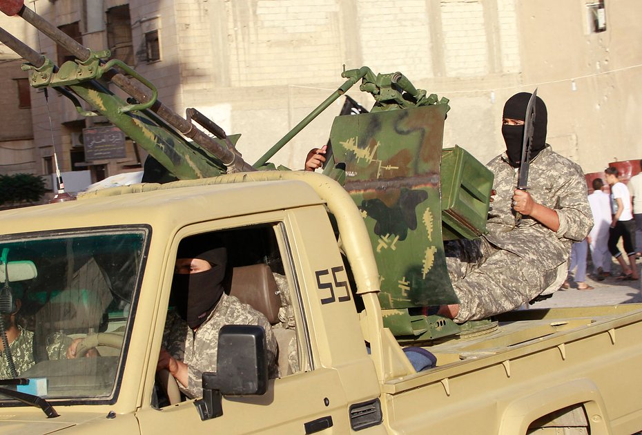 Боевики-исламисты едут в автомобиле во время военного парада в сирийской провинции Ракка, 30 июня 2014 года