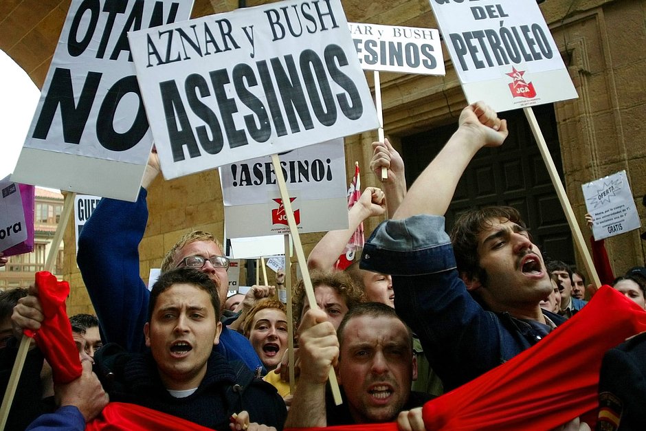 Участники антивоенной демонстрации с транспарантами «Аснар и Буш — убийцы», «Нет НАТО» и «Нет нефтяной войне» на улицах Овьедо, Испания, 11 марта 2003 года