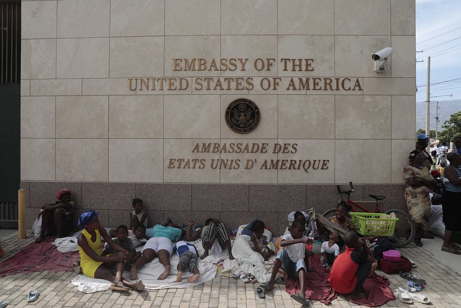 Жители района Табарре, покинувшие свои дома из-за вооруженных столкновений, отдыхают у здания посольства США в Порт-о-Пренсе, Гаити, 25 июля 2023 года