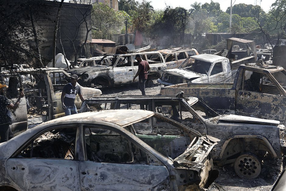 Люди ищут запасные части от сгоревших автомобилей, подожженных бандитами во время беспорядков в Порт-о-Пренсе, Гаити, 25 марта 2024 года