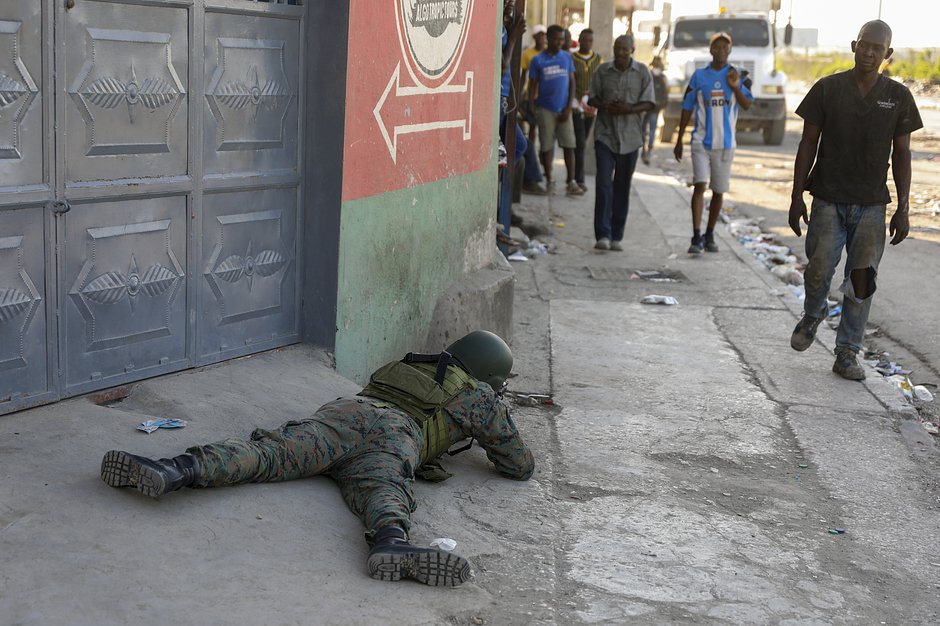 Пешеходы проходят мимо солдата, охраняющего территорию международного аэропорта в Порт-о-Пренсе, Гаити, 4 марта 2024 года