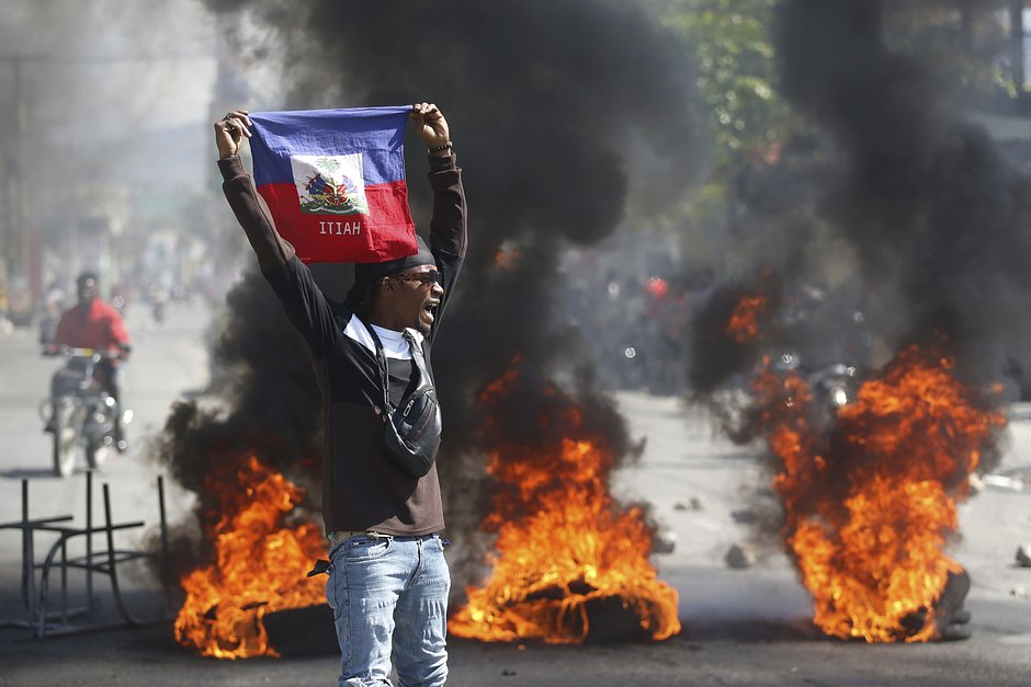 Протестующий держит гаитянский флаг во время демонстраций в Порт-о-Пренсе, Гаити, 1 марта 2024 года