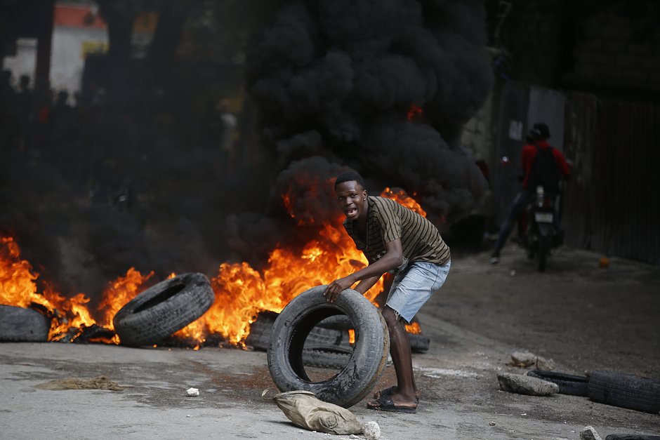 Протестующий поджигает автомобильные шины во время демонстрации с требованием отставки премьер-министра Ариэля Анри, Порт-о-Пренс, Гаити, 7 февраля 2024 года