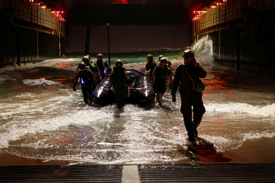 Солдаты используют боевой резиновый разведывательный корабль Combat Rubber Raid Craft во время военных тренировок на колодезной палубе внутри JS Osumi (LST-4001) в водах недалеко от Окинавы, Япония, 14 ноября 2023 года