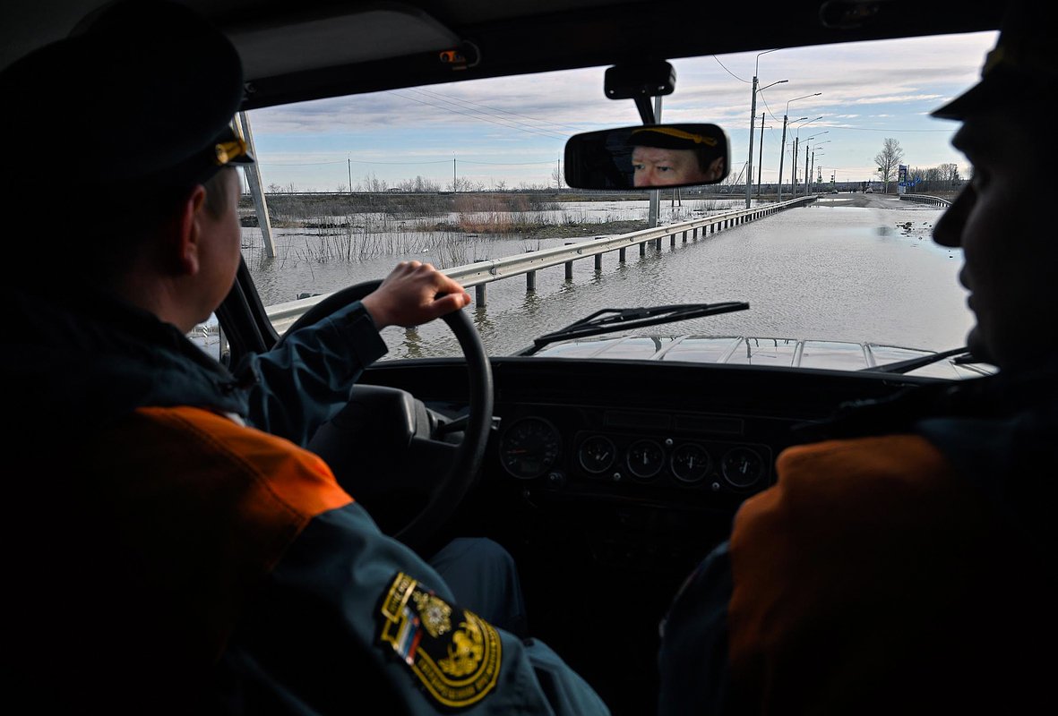 Сотрудники МЧС России в автомобиле на фоне перелива реки Тобол через шоссе. Курганская область