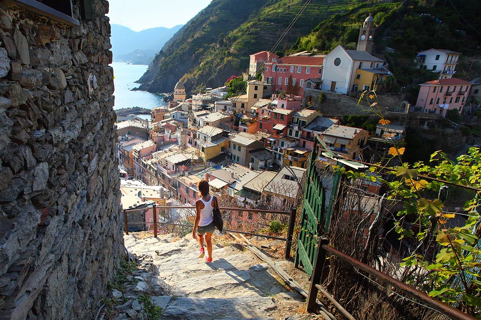 Молодая женщина, идущая по лестнице небольшой улицы города Вернацца, Италия