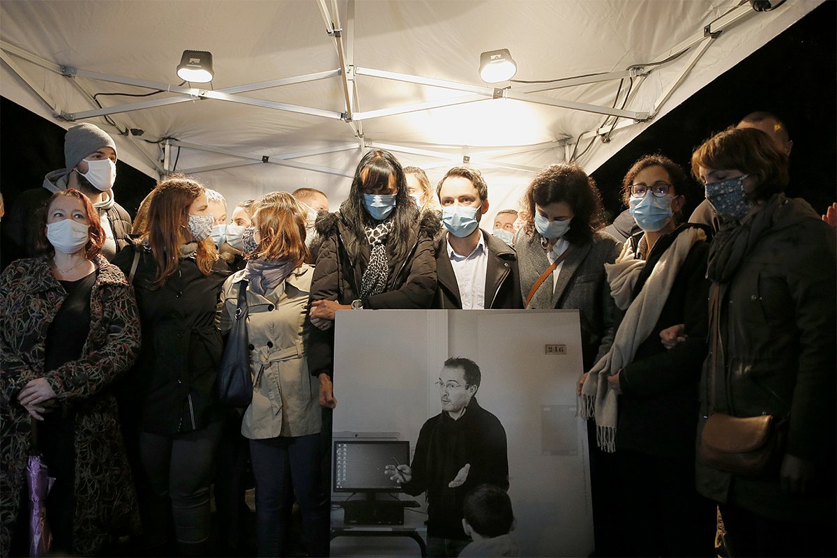 Люди держат фотографию учителя истории Сэмюэля Пати, который был обезглавлен террористами в Конфлан-Сент-Онорин, к северо-западу от Парижа, 20 октября 2020 года