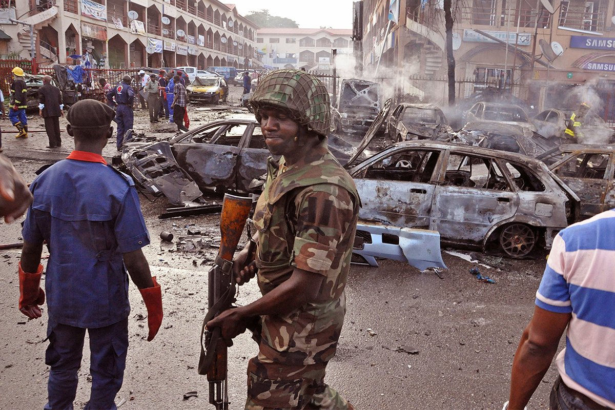 Солдат Вооруженных сил Нигерии рядом с местом взрыва, предположительно, устроенного террористами «Боко Харам», в Абудже, Нигерия, 25 июня 2014 года