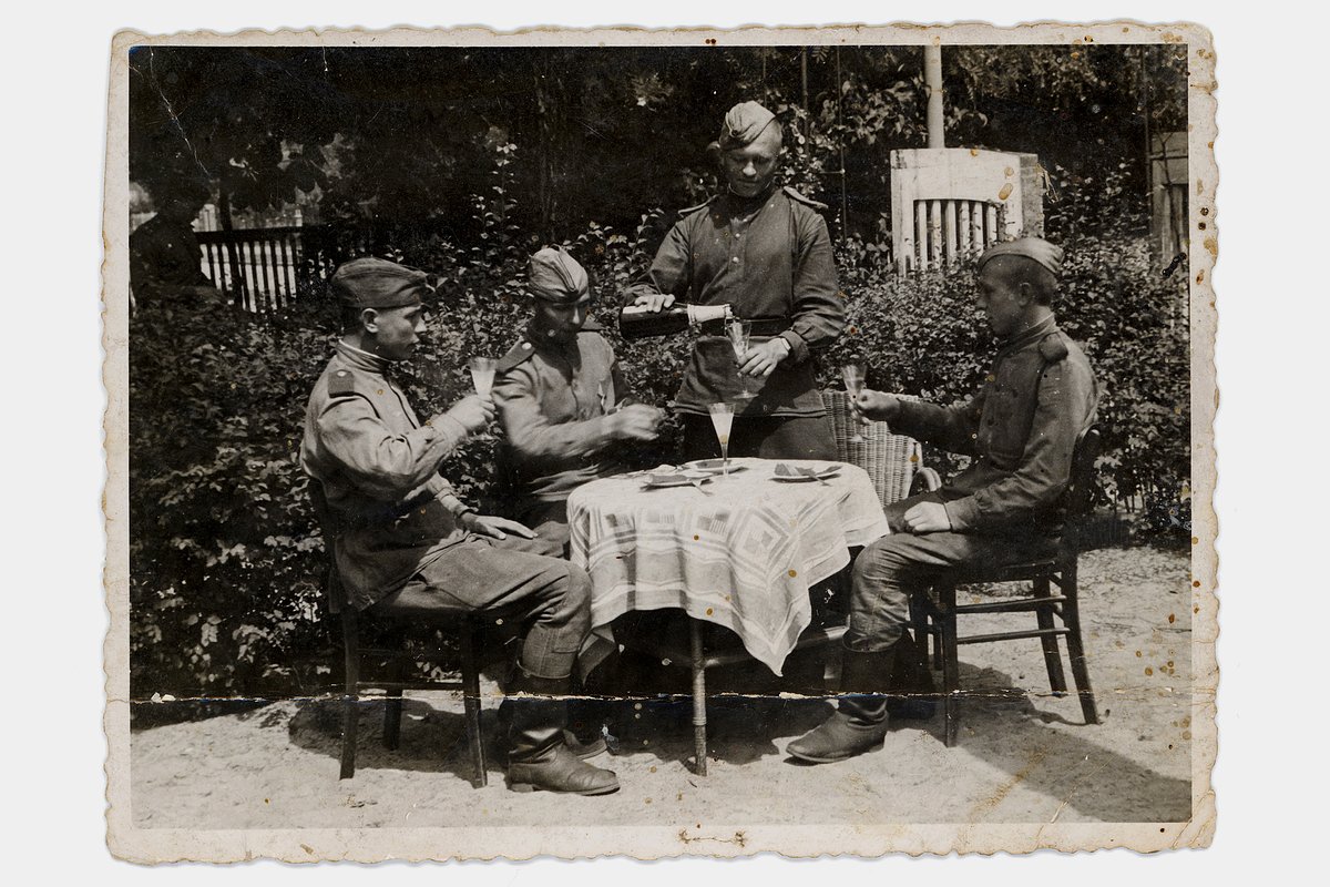Советские военные празднуют Победу, разливая по фужерам шампанское и сидя за немецким обеденным столом во дворе немецкого дома. Берлин, Германия. 17 июня 1945 года
