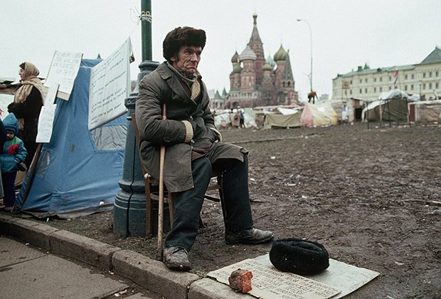 Бездомный мужчина сидит у палаточного городка, 1990 год