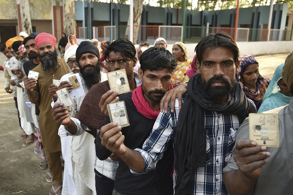 Избиратели показывают удостоверения личности в очереди на голосование на участке у Амритсара, Индия, 1 июня 2024 года 