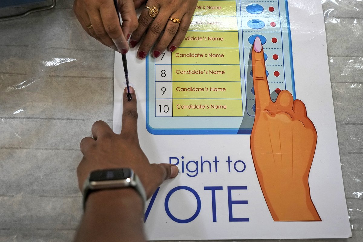 Сотрудник избирательной комиссии наносит чернильную метку на палец избирателя на участке в Нью-Дели, Индия, 25 мая 2024 года 
