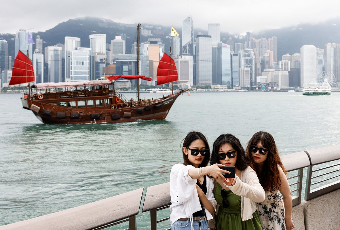 Туристы фотографируются на фоне бухты Виктории в Гонконге