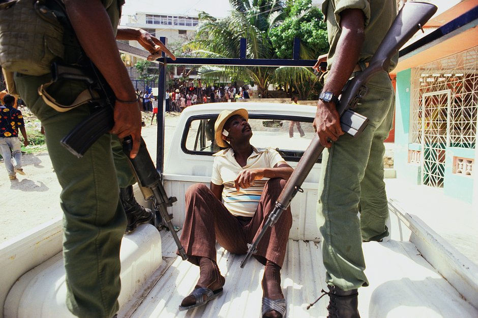 Двое солдат охраняют мужчину в кузове пикапа, Порт-о-Пренс, Гаити, 1 февраля 1986 года