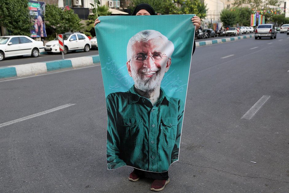 Мужчина держит баннер с портретом кандидата в президенты Ирана Саида Джалили перед митингом в его поддержку, Тегеран, Иран, 19 июня 2024 года