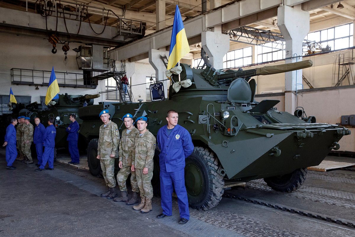 Рабочие и военнослужащие Вооруженных сил Украины стоят возле бронетехники во время пресс-тура на Киевский бронетанковый завод